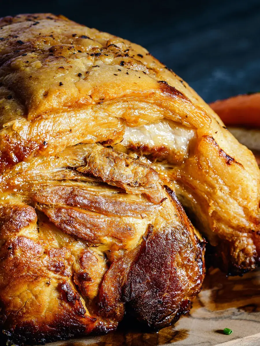 Slow-roasted pork shoulder with crisp golden skin and glazed carrots